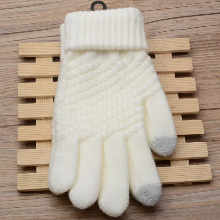 Weiße gestrickte Winterhandschuhe aus Wolle mit grauen Fingerspitzen auf Holzuntergrund.