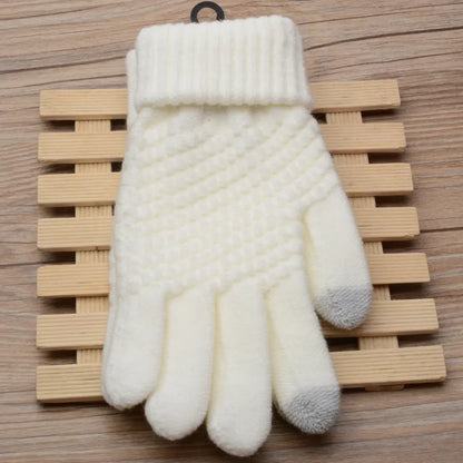 Weiße gestrickte Winterhandschuhe aus Wolle mit grauen Fingerspitzen auf Holzuntergrund.