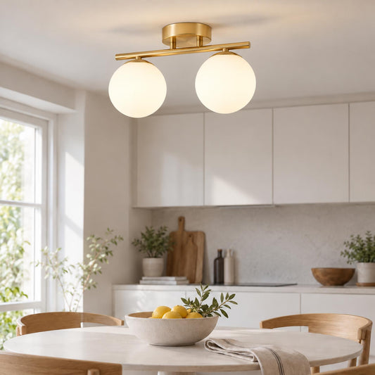 Lampa med två glaskulor på mässingsfärgad skena ovanför matbord med citronskål i ljust kök 2
