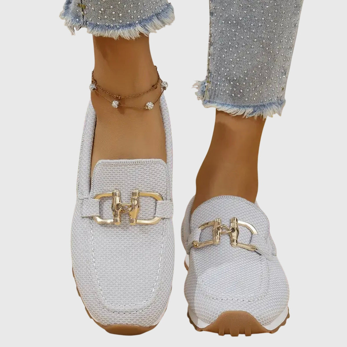 Ljusgrå mesh-loafers med guldspänne sedda rakt framifrån på modell 9