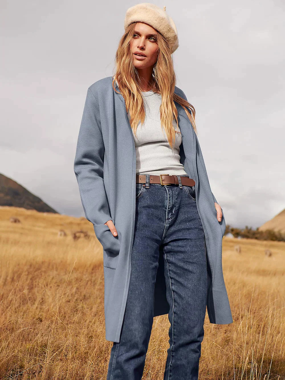 Frau in blauem Mantel und Jeans, beige Mütze, Herbstlandschaft, Mode, Outdoor-Bekleidung.