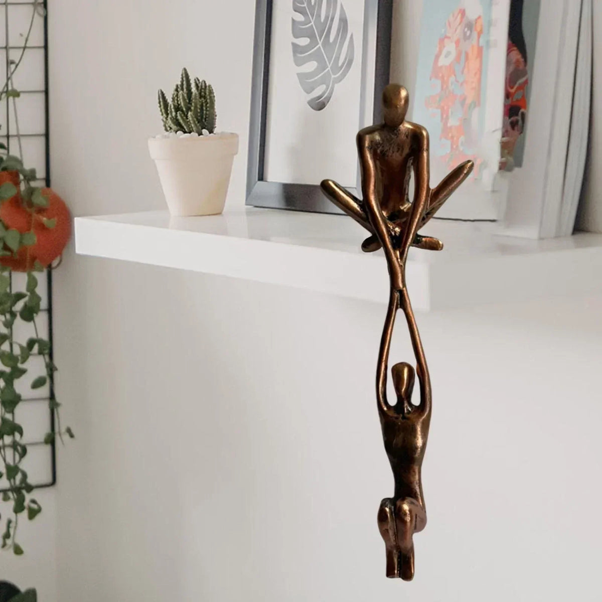 Bronzeskulptur von zwei Figuren, moderne Kunst, auf weißem Regal, dekorative Wohnaccessoires.