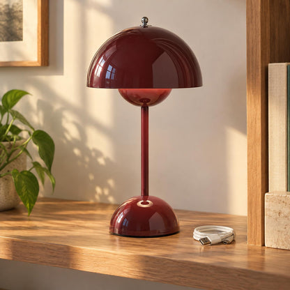 Vinröd lampa med svampformad skärm på en trähylla bredvid en vas, med USB-kabel framför 1