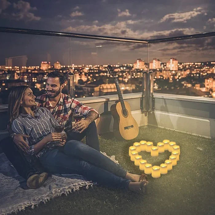 Paar auf Dachterrasse bei Nacht, umgeben von Kerzen in Herzform, Gitarre im Hintergrund.