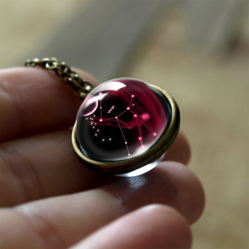 Hand hält bronzenen Anhänger mit rotem Glas und Sternbild-Design, Vintage-Schmuck, Astrologie.