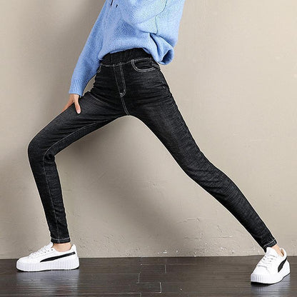 Frau in blauer Strickjacke und schwarzen Jeans-Leggings, weiße Sneaker, modisch, bequem.