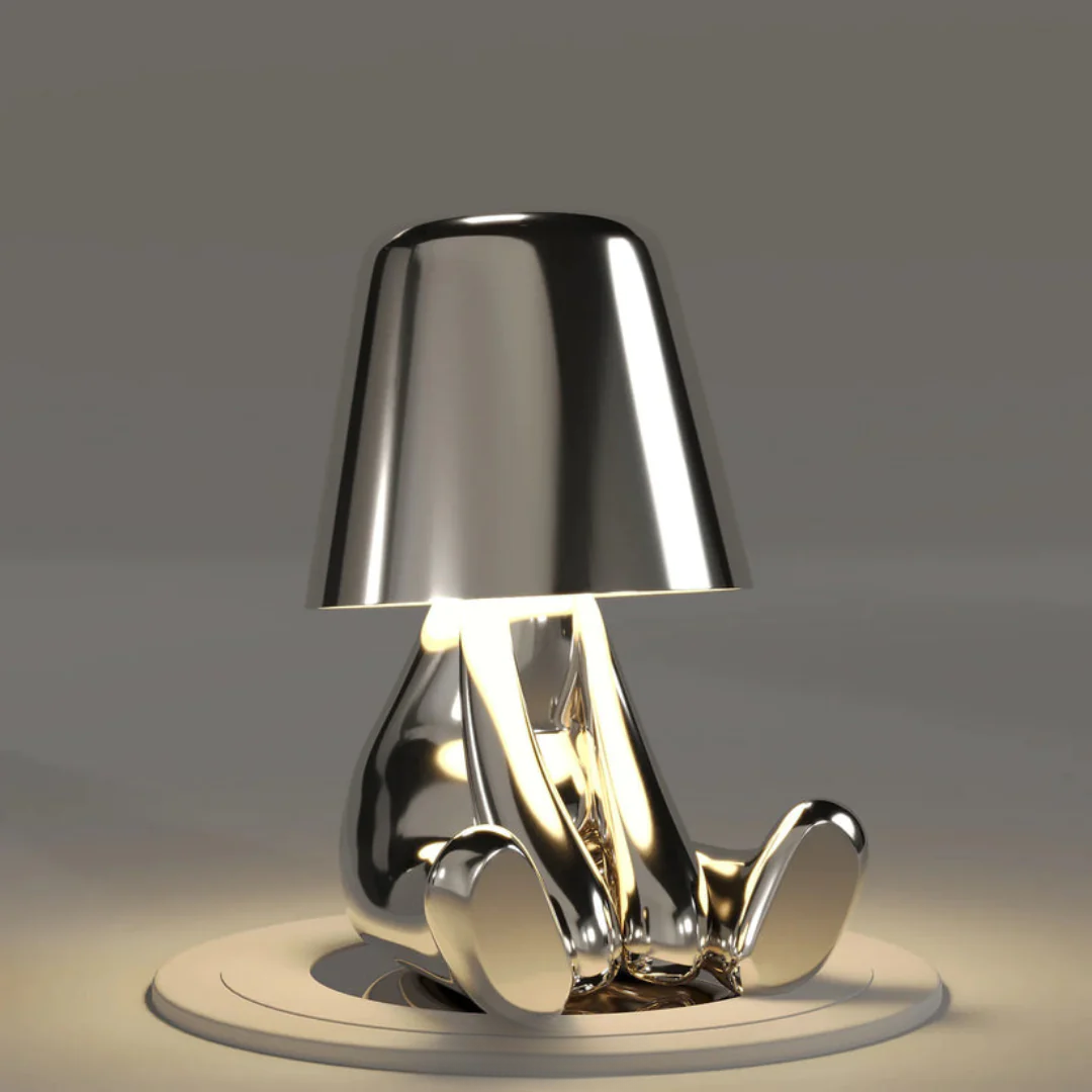 Silberne Tischlampe in Form einer sitzenden Figur, modernes Design, glänzend, dekorativ.