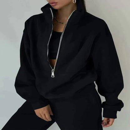 Frau in schwarzem Reißverschluss-Sweatshirt und Hose, modisch, lässig, Streetwear-Look.