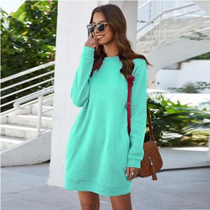 Frau in mintgrünem Sweatshirt-Kleid, Sonnenbrille, braune Tasche, lässiger Stil.
