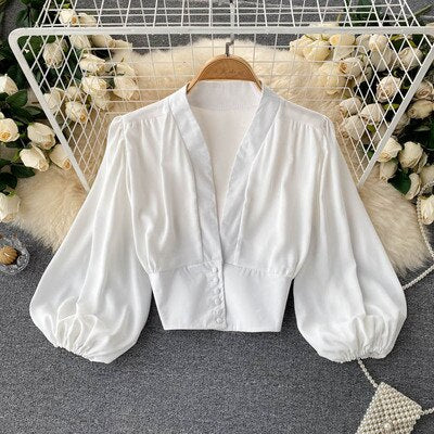 Weiße Bluse mit Puffärmeln, V-Ausschnitt, elegant, Damenmode, Baumwolle, auf Kleiderbügel.