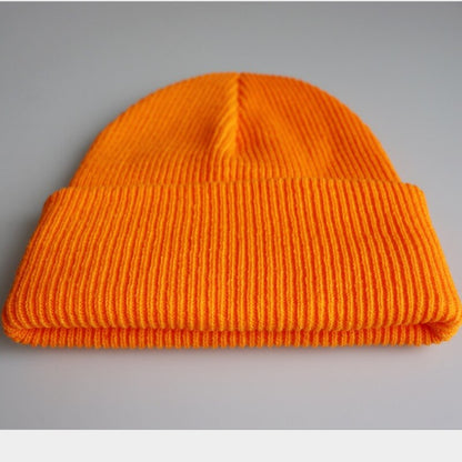 Orangefarbene Strickmütze aus Wolle, modisches Accessoire für Herbst und Winter.