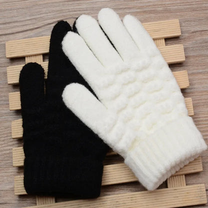 Schwarze und weiße Strickhandschuhe aus Wolle auf Holzunterlage, Wintermode Accessoires.