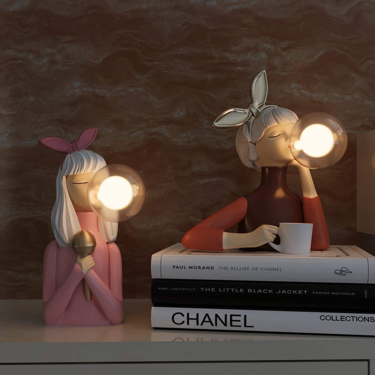 Zwei dekorative Tischlampen in Form von Figuren mit Glühbirnen, rosa und braun, auf Bücherstapel.