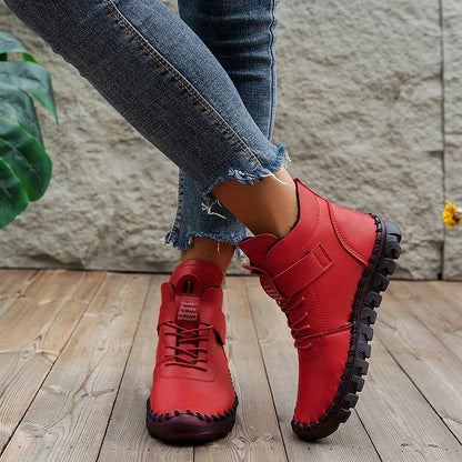 Rote Damenstiefel aus Leder, lässig, mit Schnürung, auf Holzfußboden, modisch, bequem.