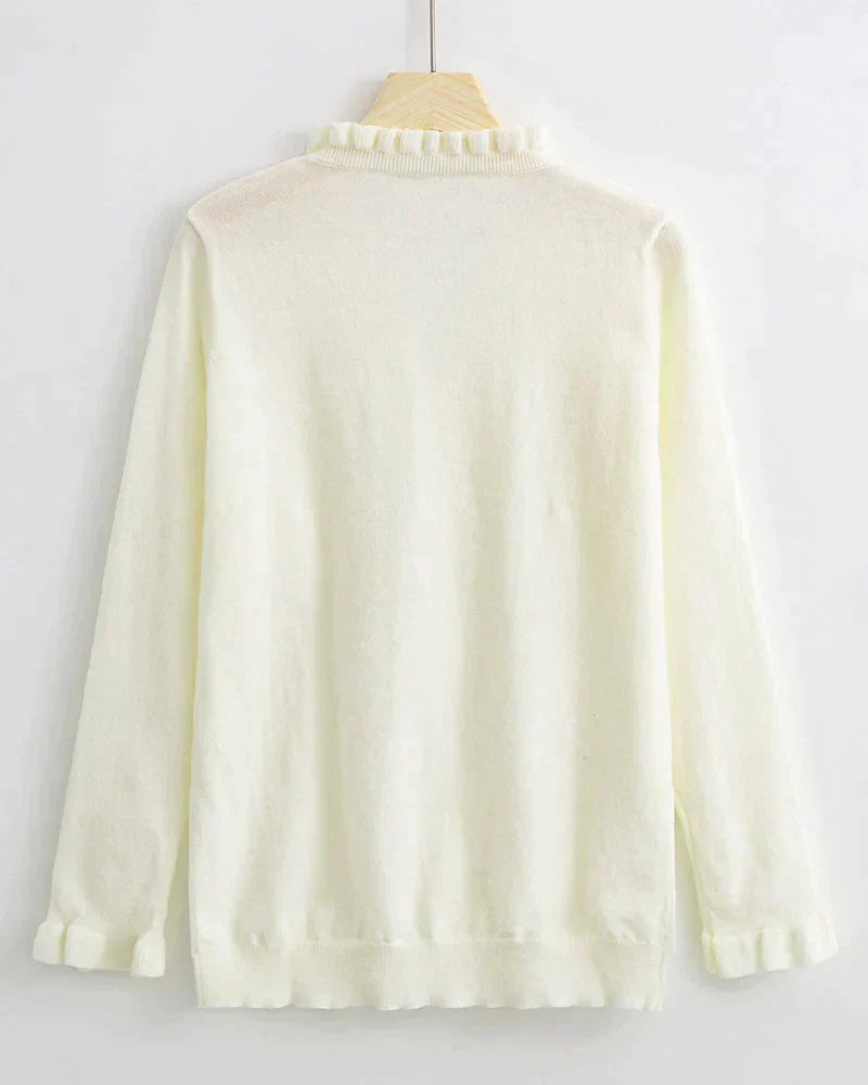 Weiße Damenstrickjacke mit Rüschenkragen, langärmelig, aus weichem Material, elegant und stilvoll.