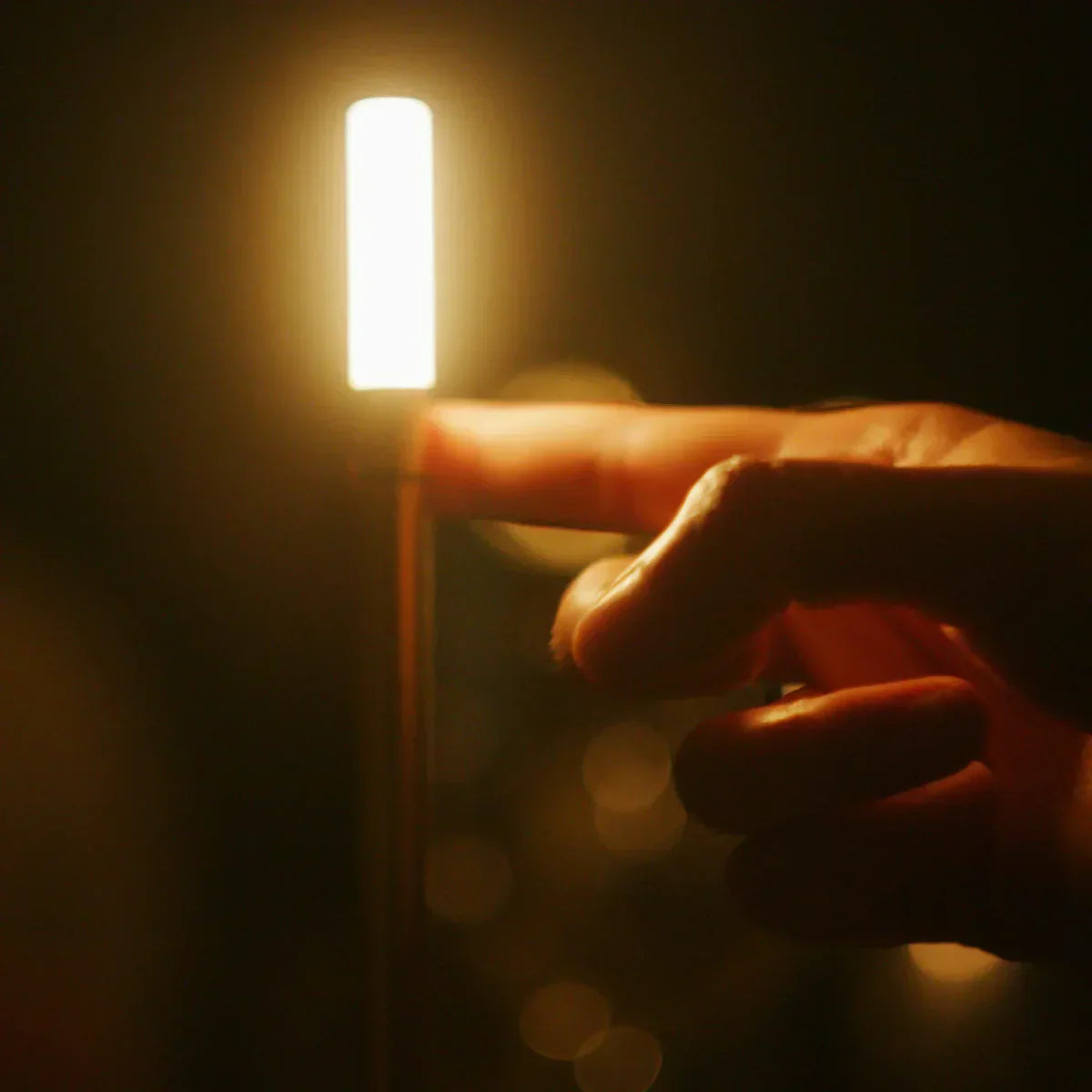 Finger berührt leuchtende LED-Lampe, warmes Licht, dunkler Hintergrund, moderne Beleuchtung.
