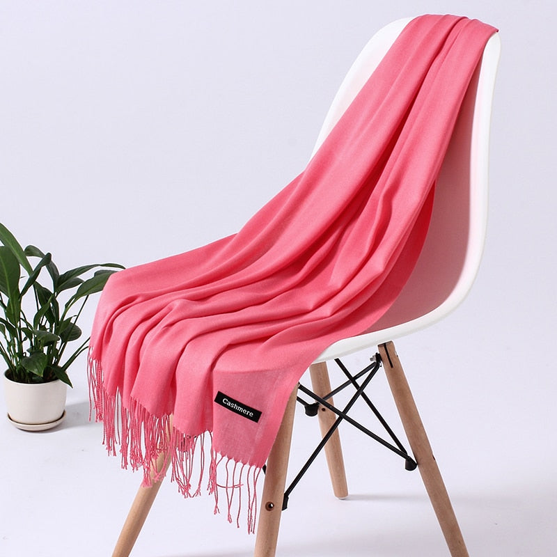 Rosa Kaschmirschal auf weißem Stuhl, weiches Material, modisches Accessoire, Wohnzimmer.