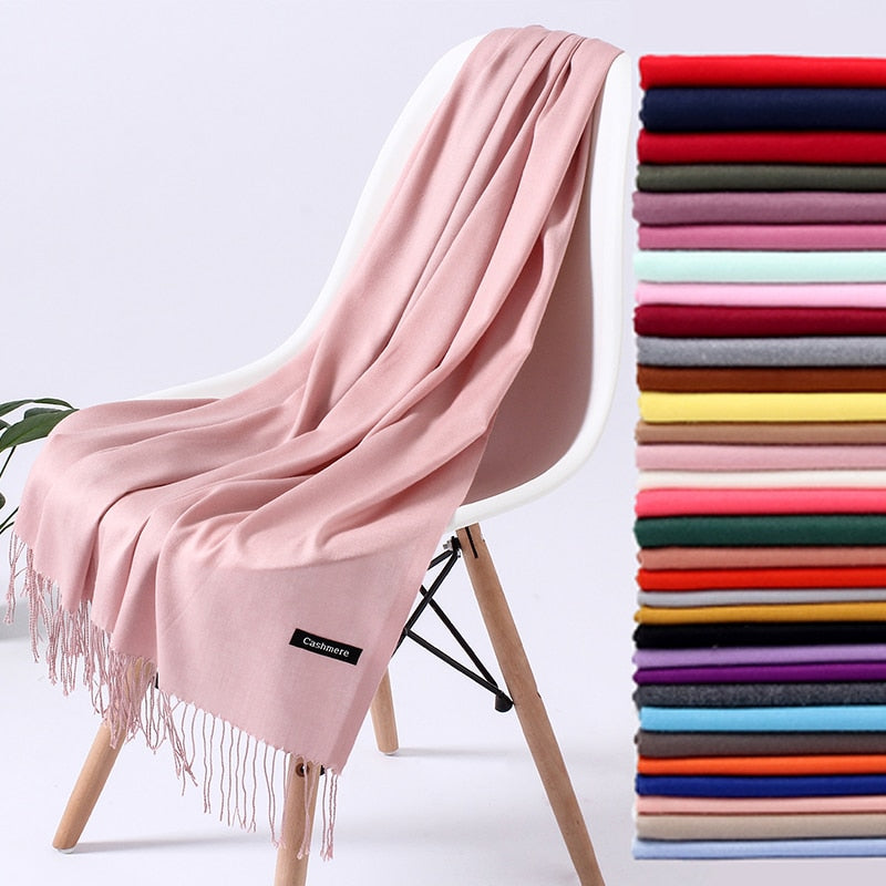 Rosa Kaschmirschal auf Stuhl, weiches Material, Fransen, verschiedene Farben, modisches Accessoire.