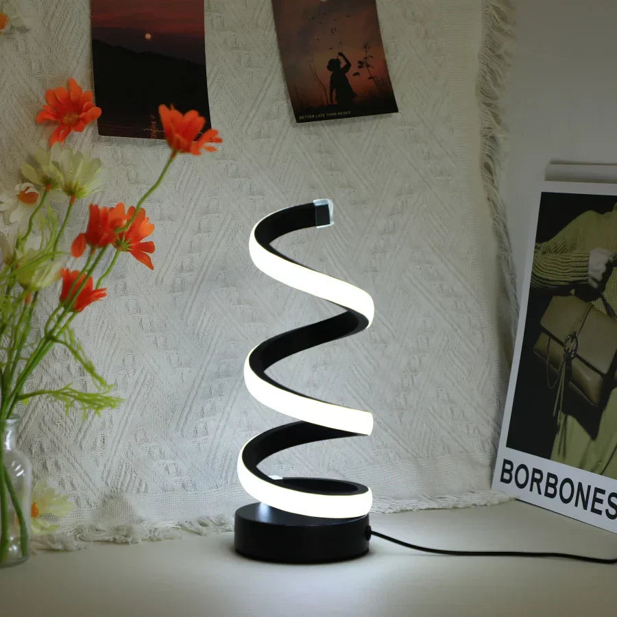 Schwarze LED-Tischlampe in Spiralform, modernes Design, leuchtend, auf weißem Tisch.