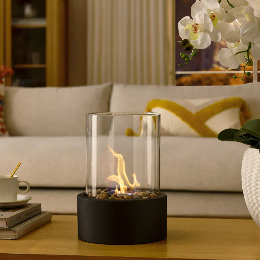 Tischkamin Glaszylinder mit Flamme, schwarzer Sockel, Wohnzimmer, moderne Dekoration.
