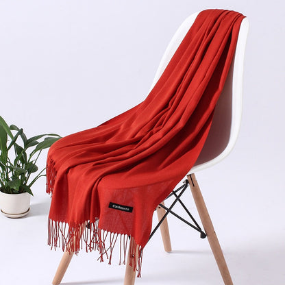 Roter Kaschmirschal auf Stuhl, weiches Material, modisches Accessoire, Wohnzimmerdekoration.