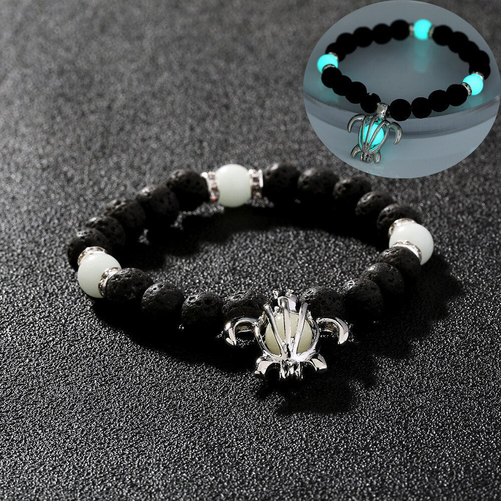 Schwarzes Lavastein-Armband mit leuchtenden Perlen und silbernem Lotus-Anhänger.