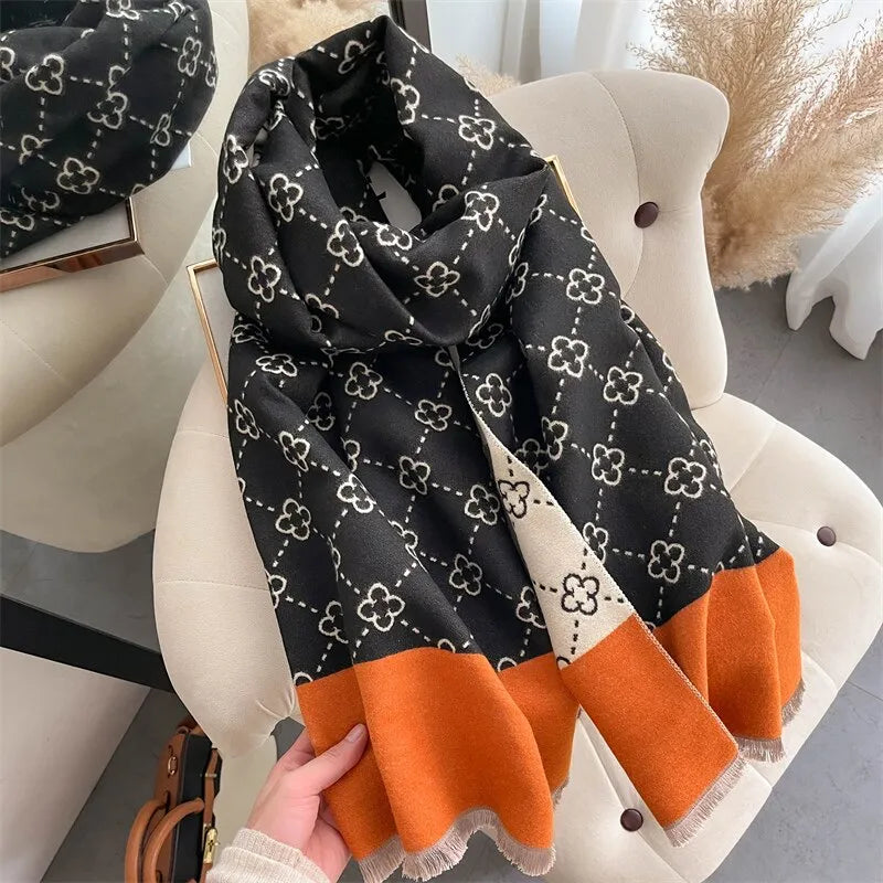 Schwarzer Schal mit Blumenmuster, orangefarbener Rand, weiches Material, modisches Accessoire.