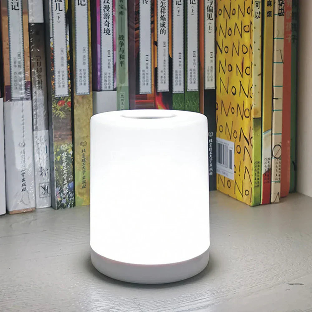 LED-Tischlampe mit stufenloser Dimmung, Touch-Steuerung, USB-aufladbar, weiß, vor Bücherregal.