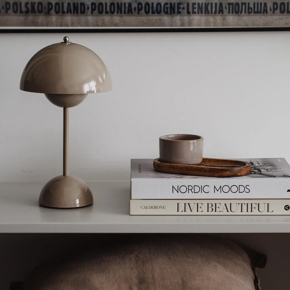 Beige Tischlampe auf weißem Regal mit Büchern und Tasse, skandinavisches Design, Wohnzimmer-Dekor.