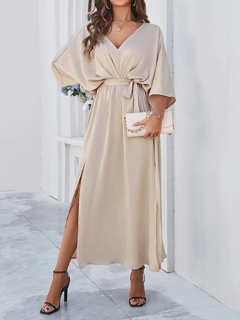 Frau in beigem V-Ausschnitt-Kleid mit Gürtel, elegantes Frühlingsoutfit, High Heels, Clutch.