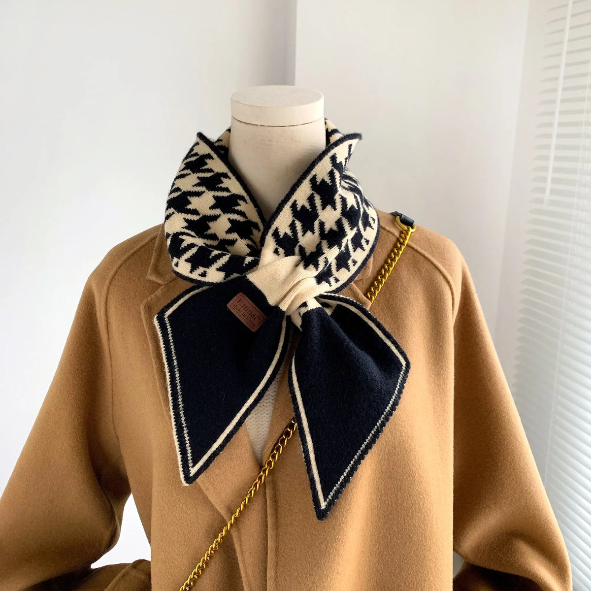 Damenmantel beige mit schwarz-weißem Schal, Hahnentrittmuster, elegantes Winteroutfit.