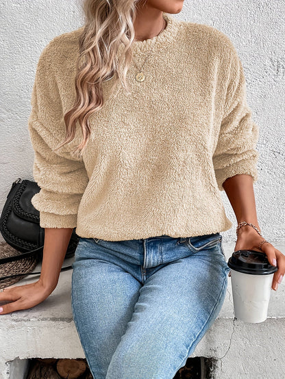 Frau in beigem Fleece-Pullover, blaue Jeans, hält Kaffeebecher, modisch, lässiger Look.