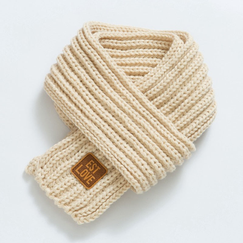 Beiger Strickschal aus Wolle mit Etikett, modisches Accessoire für Herbst und Winter.