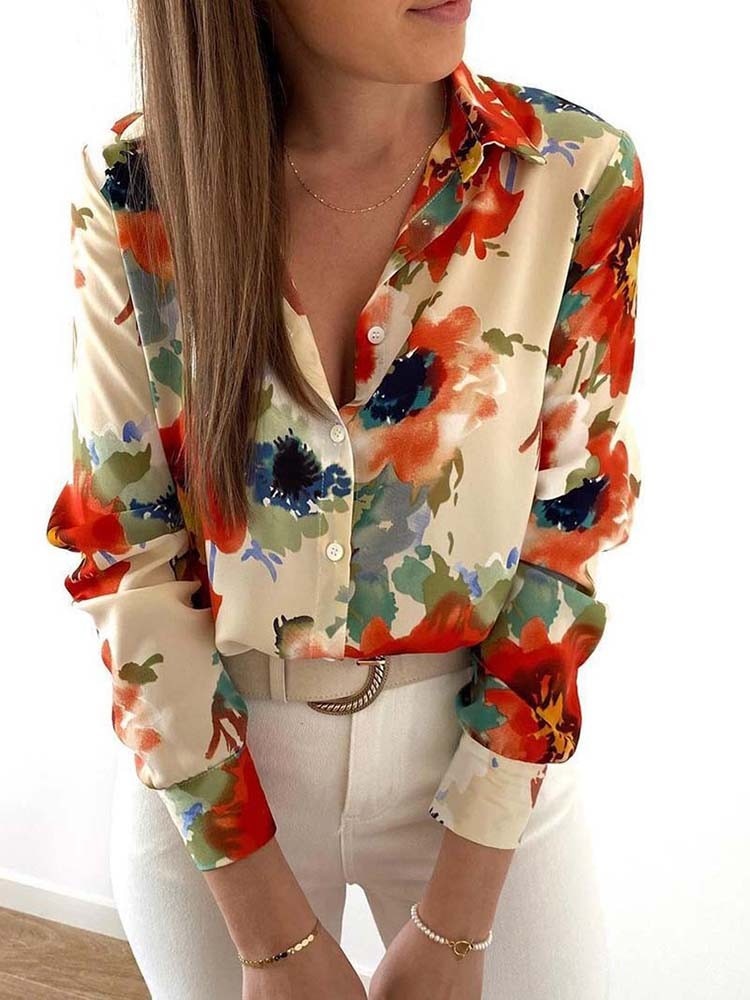 Frau in bunter Blumenbluse, lange Ärmel, V-Ausschnitt, weiße Hose, modisch, elegant.