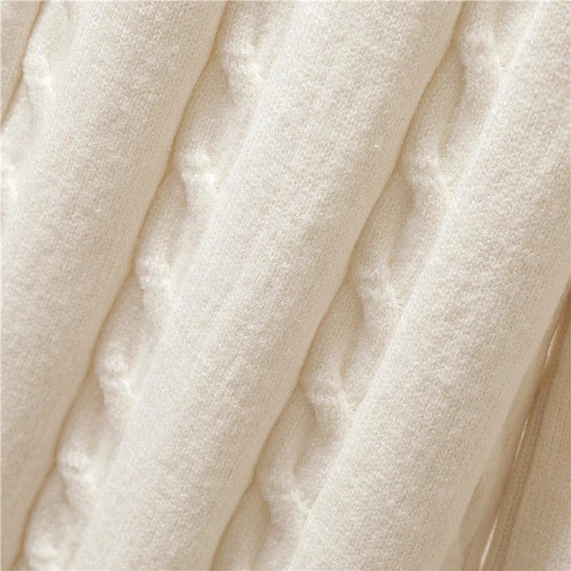 Beigefarbener Strickstoff mit Zopfmuster, weiche Textur, ideal für Pullover und Decken.