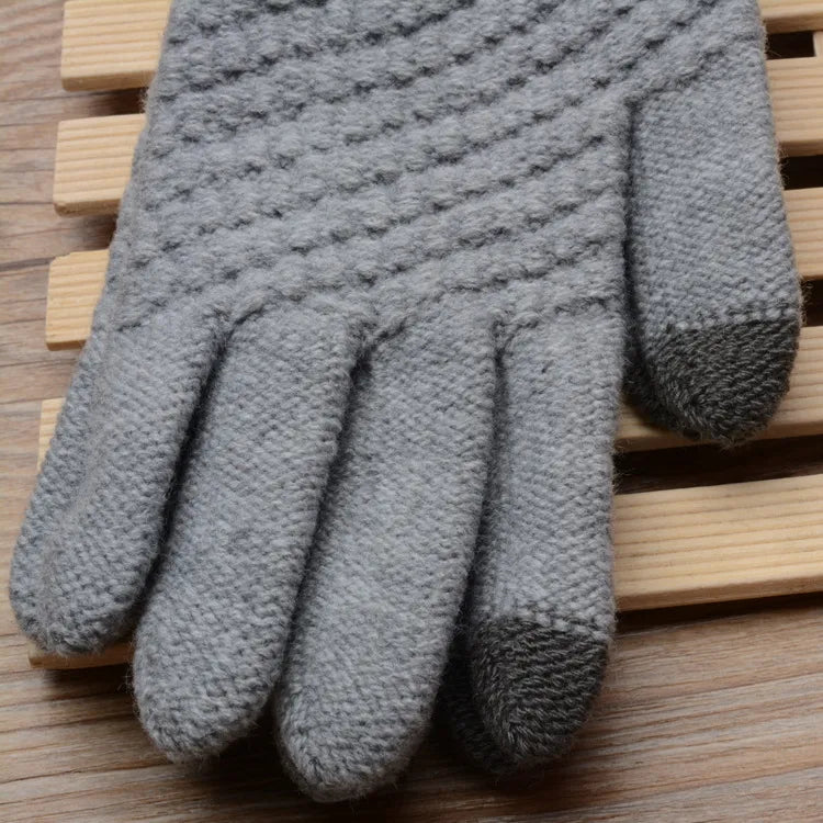 Graue gestrickte Handschuhe, rutschfest, warm, für Winter, auf Holzuntergrund.