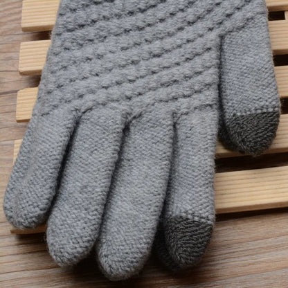 Graue gestrickte Handschuhe, rutschfest, warm, für Winter, auf Holzuntergrund.