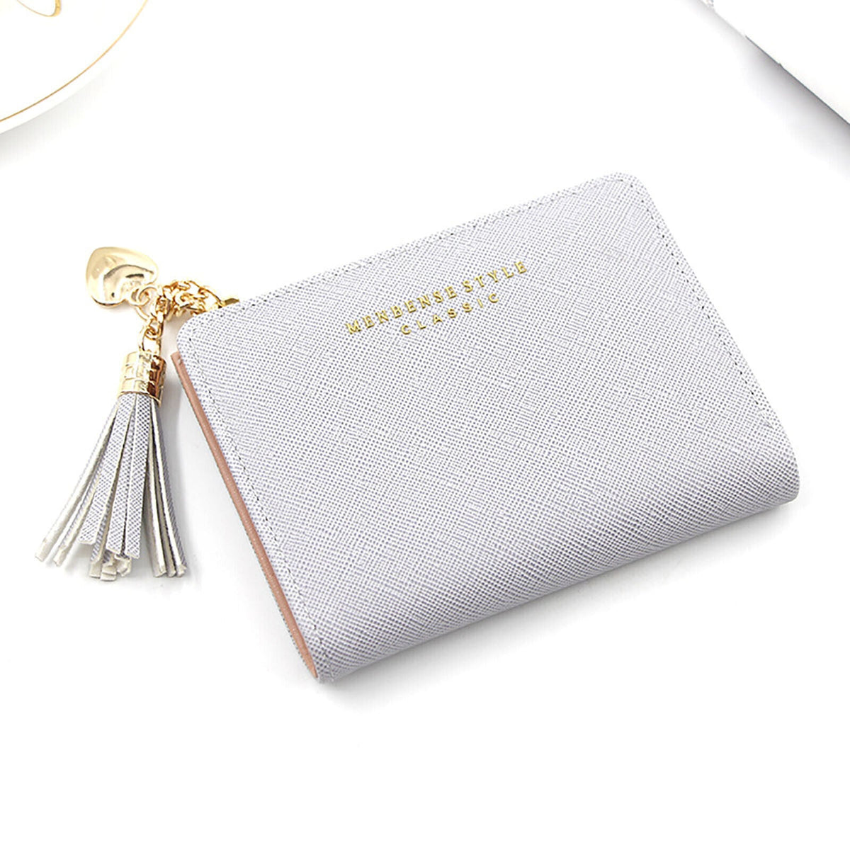 Graues Damenportemonnaie aus Leder mit Quaste und goldenen Akzenten, elegant und stilvoll.