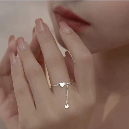 Frau mit silbernem Herzring, zarte Kette, eleganter Schmuck, romantisches Design.