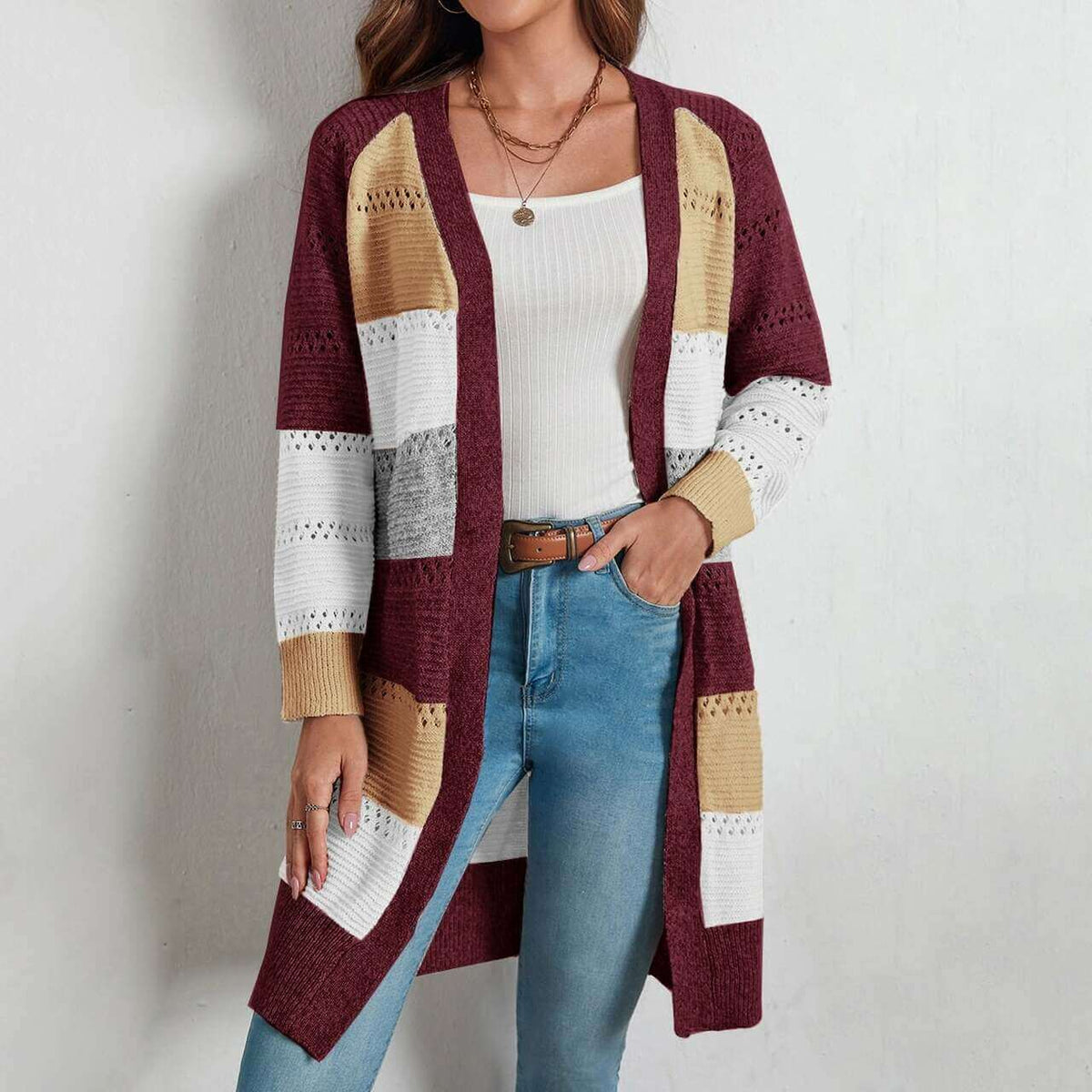 Frau trägt gestrickte Weste, mehrfarbig, lang, modisch, Herbstmode, Damenbekleidung.