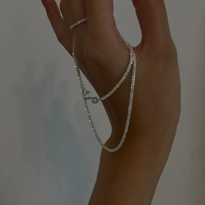 Hand mit silberner Halskette, elegantes Schmuckdesign, minimalistisch, modisch, Accessoire.