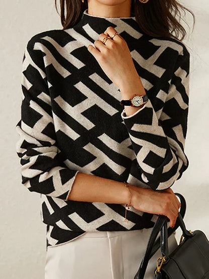 Frau in schwarz-weißem geometrischem Pullover, Armbanduhr, schwarze Handtasche.