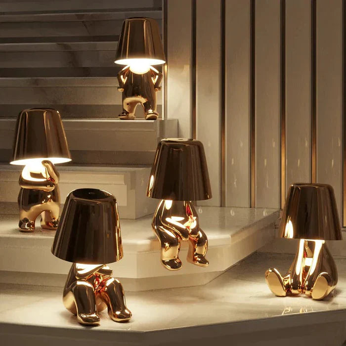 Goldene Lampen in Form von sitzenden Figuren auf Treppe, modernes Design, Innenbeleuchtung.